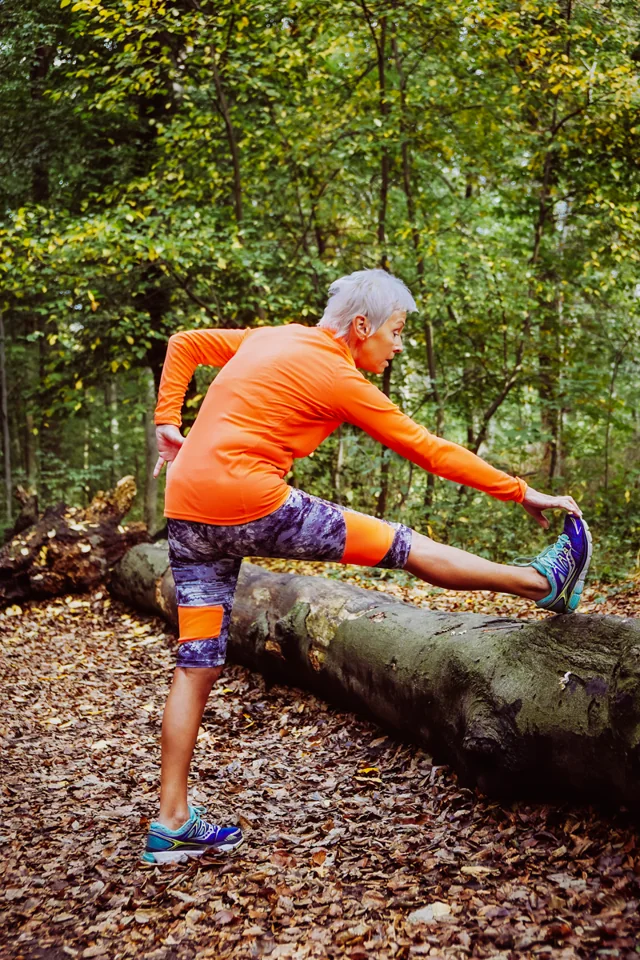 Woman stretching beside a woodland trail